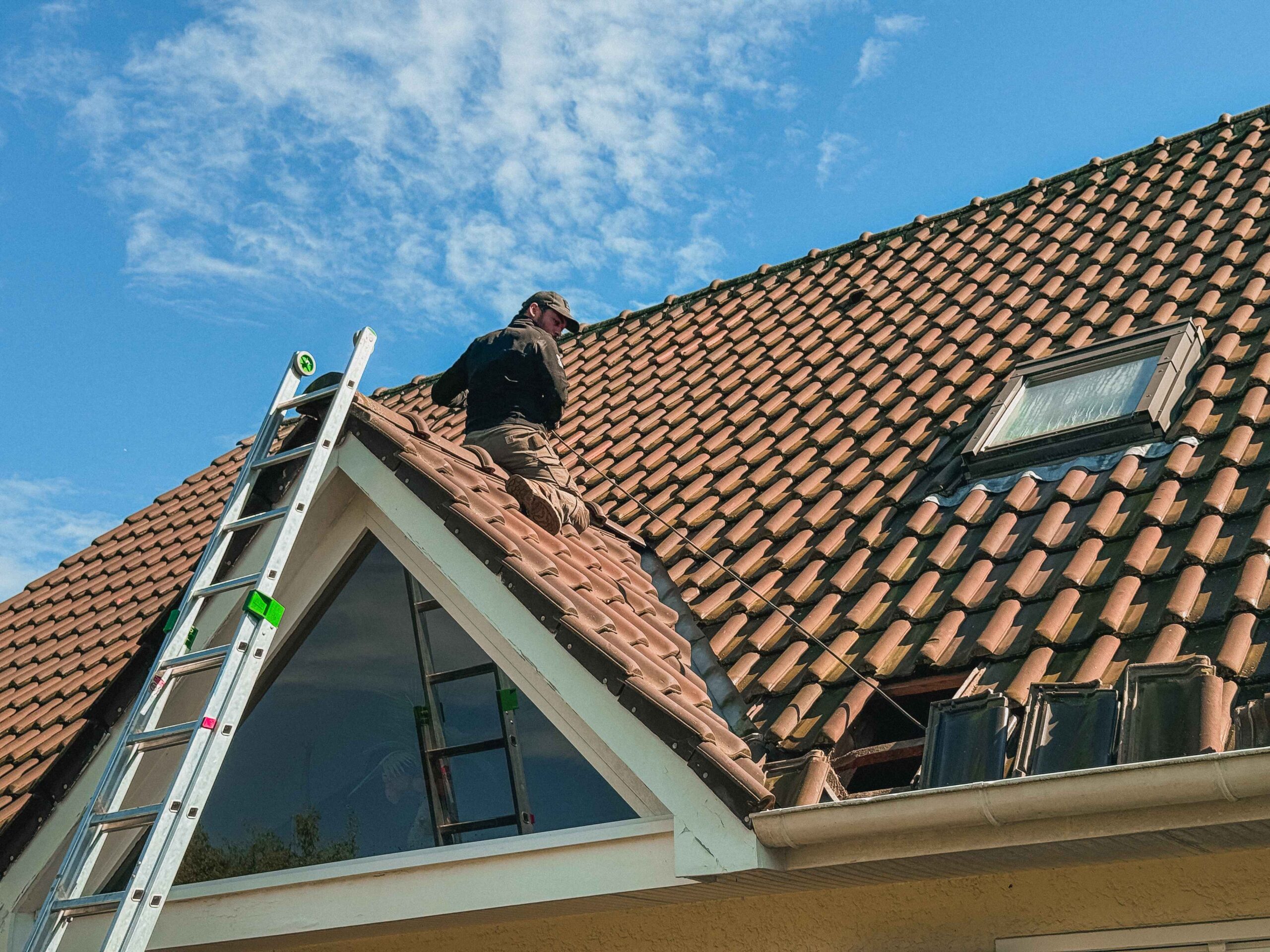 Artisan de Anov Energie sur un toit d'une maison pour le passage des câbles électriques du système de climatisation.