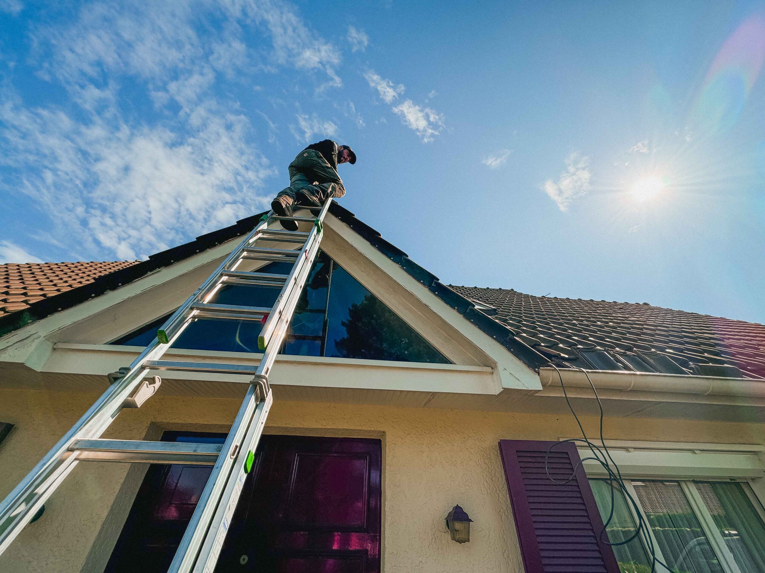 Artisan de Anov Energie sur une échelle pour installer un système de climatisation sur un toit.