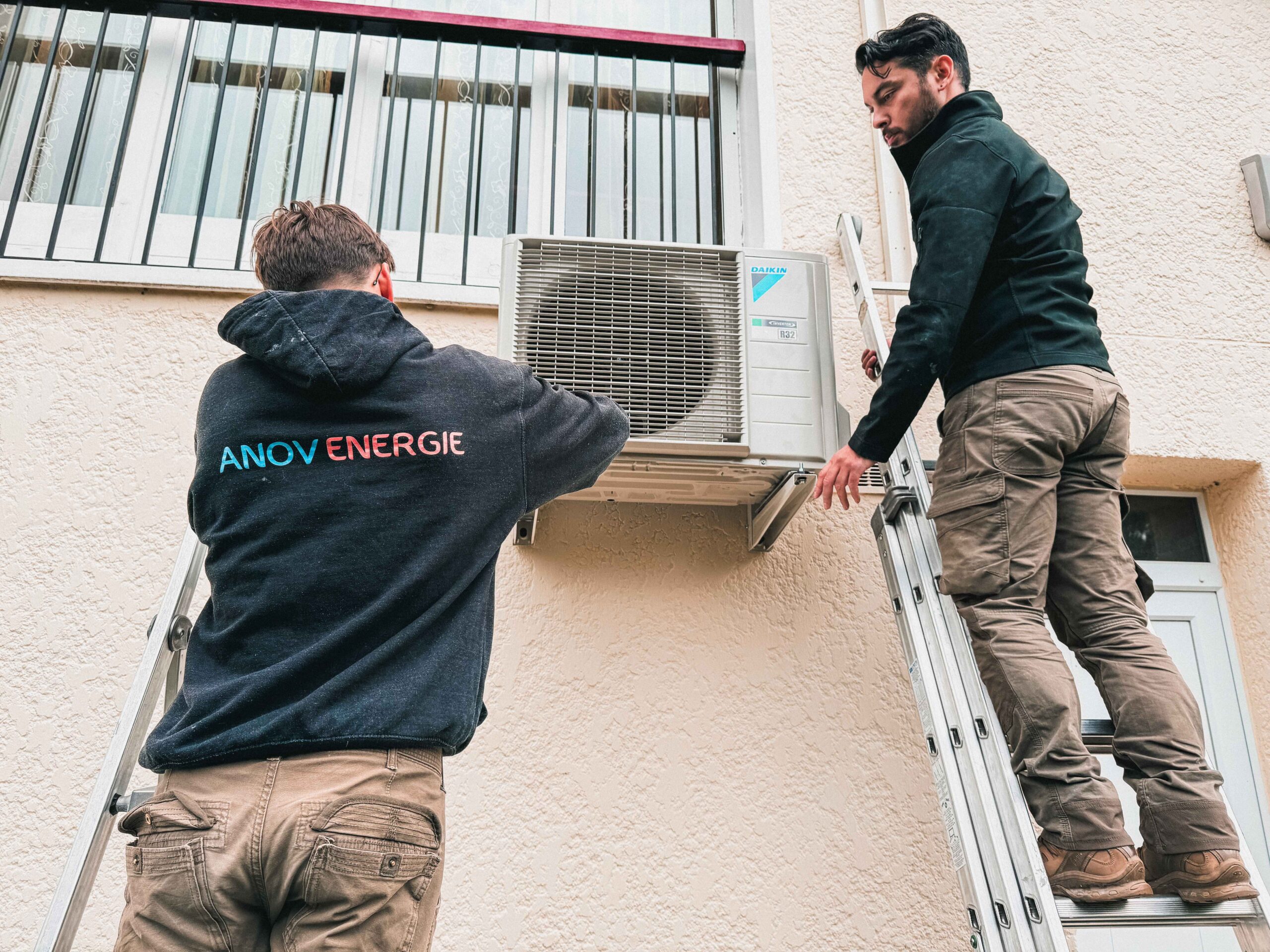 Deux artisans de Anov Energie sur des échelles pour installation d'une climatisation Daikin sur un mur pour un client à Noisy-le-Grand.